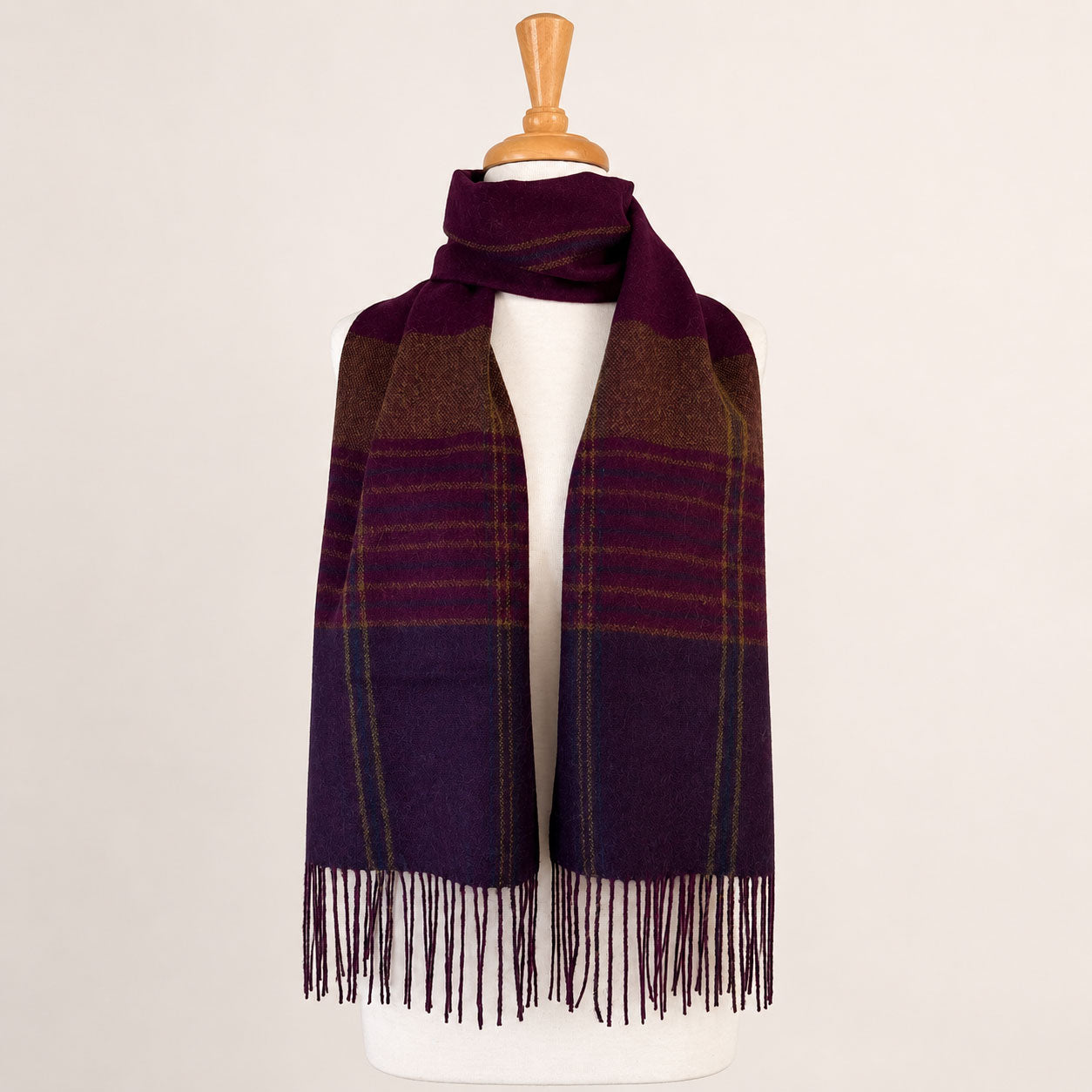 Plaid alpaca scarf with fringe on a mannequin against a plain background