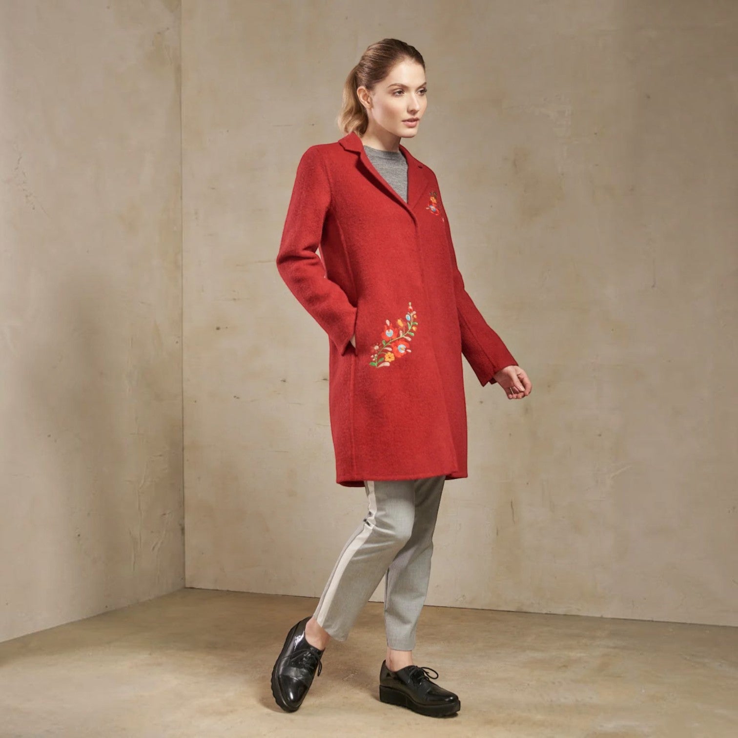 Full-length view of the Selina red baby alpaca coat styled with grey trousers and black shoes