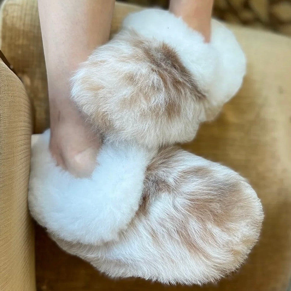 Model wearing reversible alpaca fur house slippers in a cosy home setting