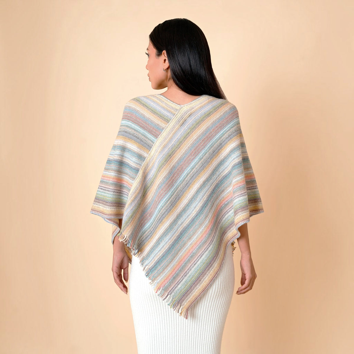 Pastel striped asymmetric alpaca poncho in soft multicoloured tones on female model