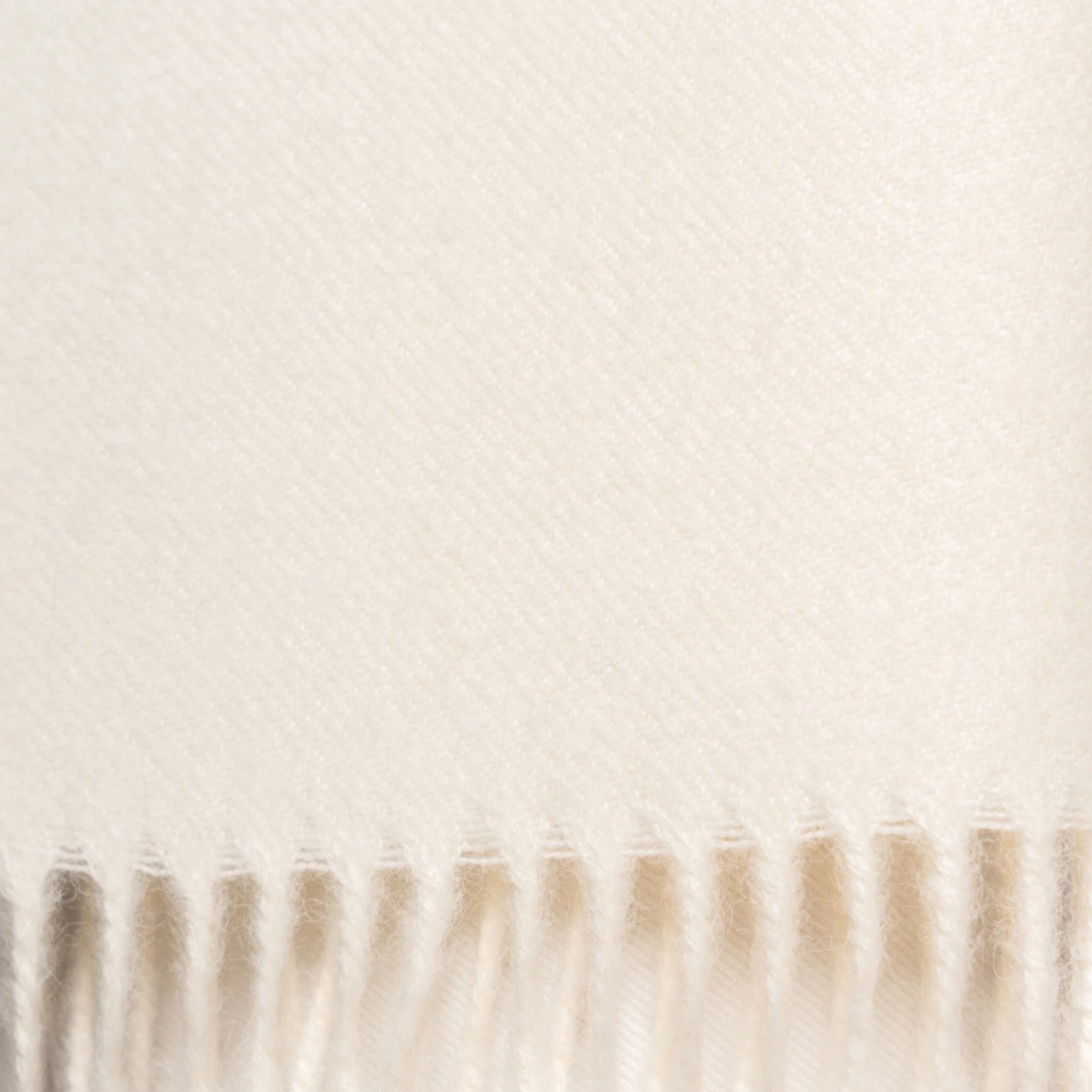 Close Up Undyed ecru alpaca scarf styled around the neck with elegant fringed ends