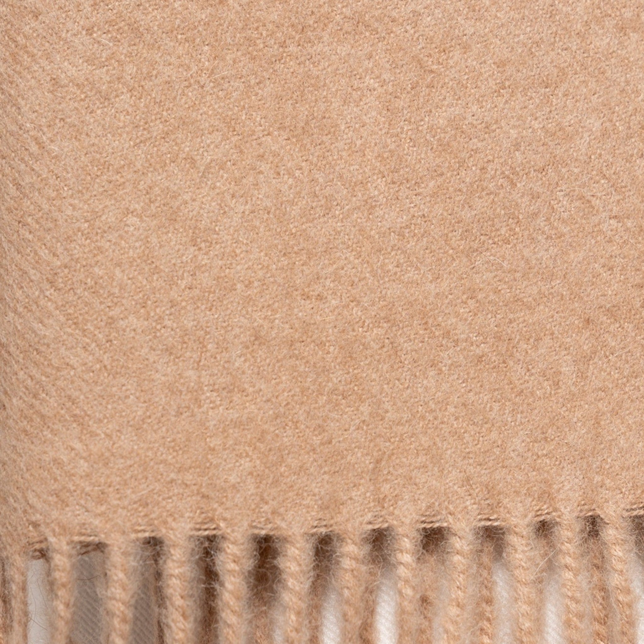Close Up Undyed beige alpaca scarf styled around the shoulders with classic fringed ends