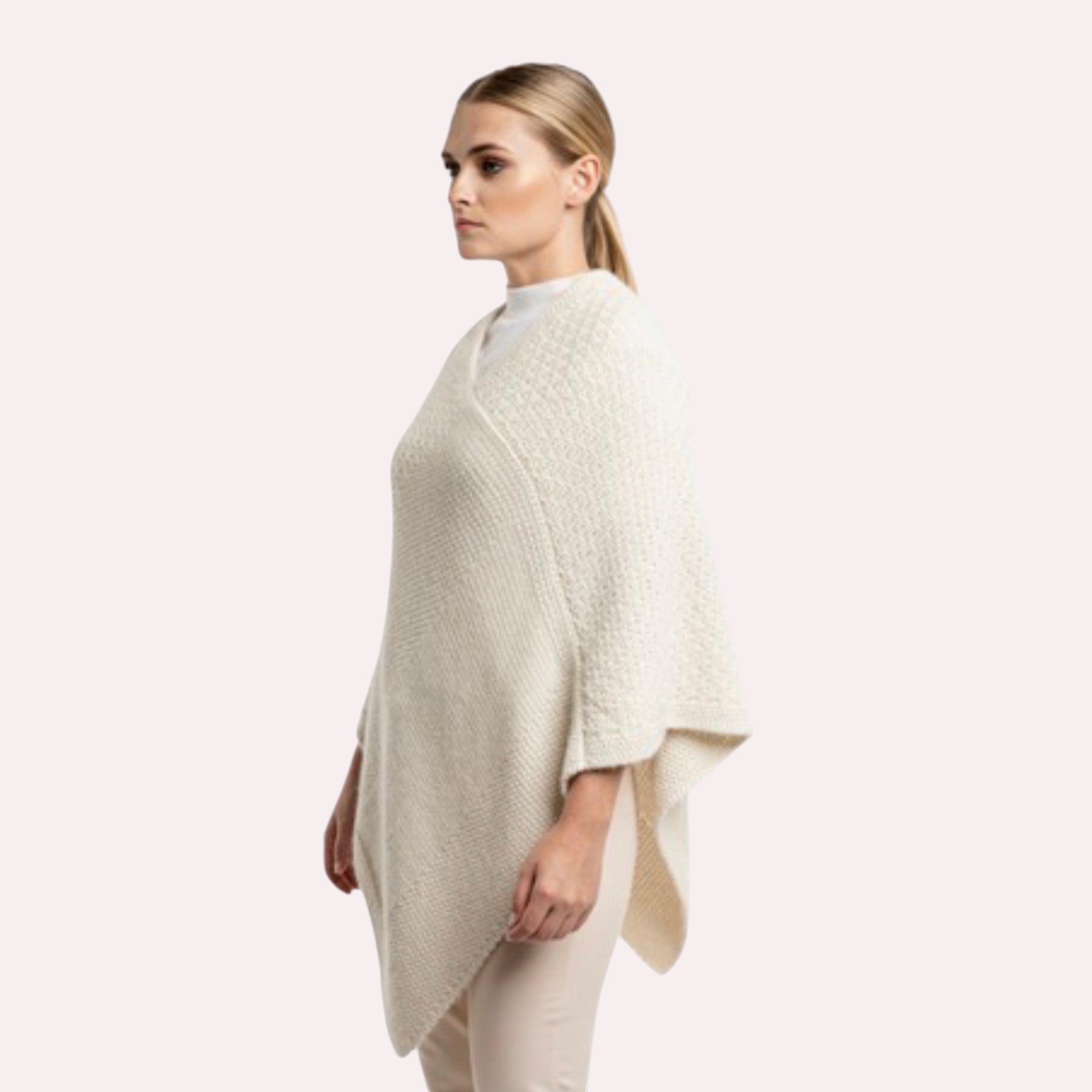 Woman wearing cream knitted alpaca poncho with neutral winter outfit.