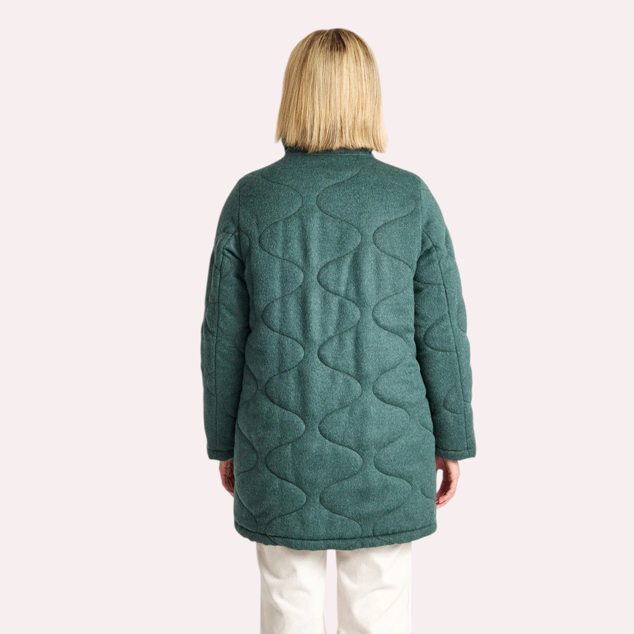 Woman wearing green padded alpaca coat with neutral winter outfit.