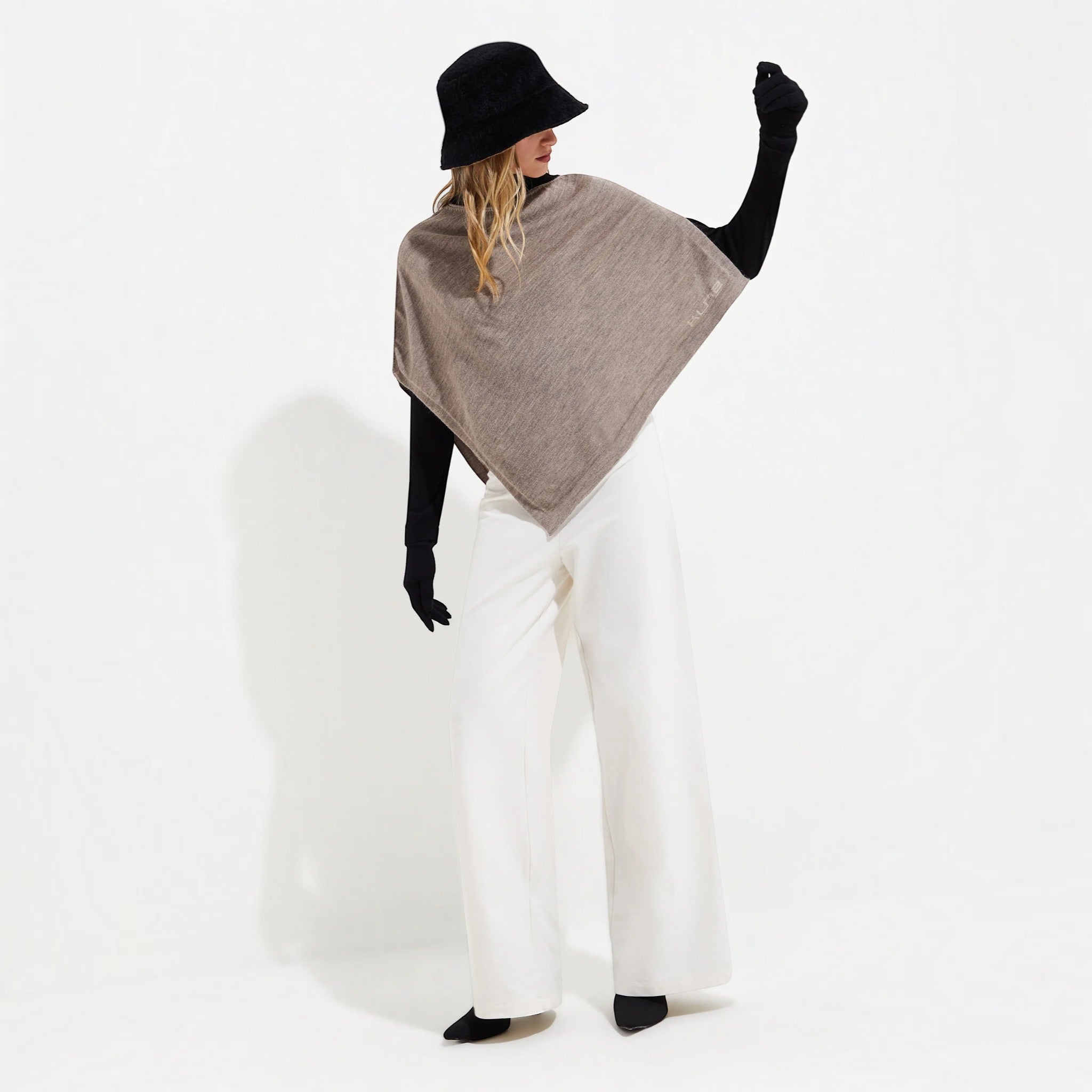Full-length view of a woman wearing the lightweight Yura alpaca silk poncho in taupe