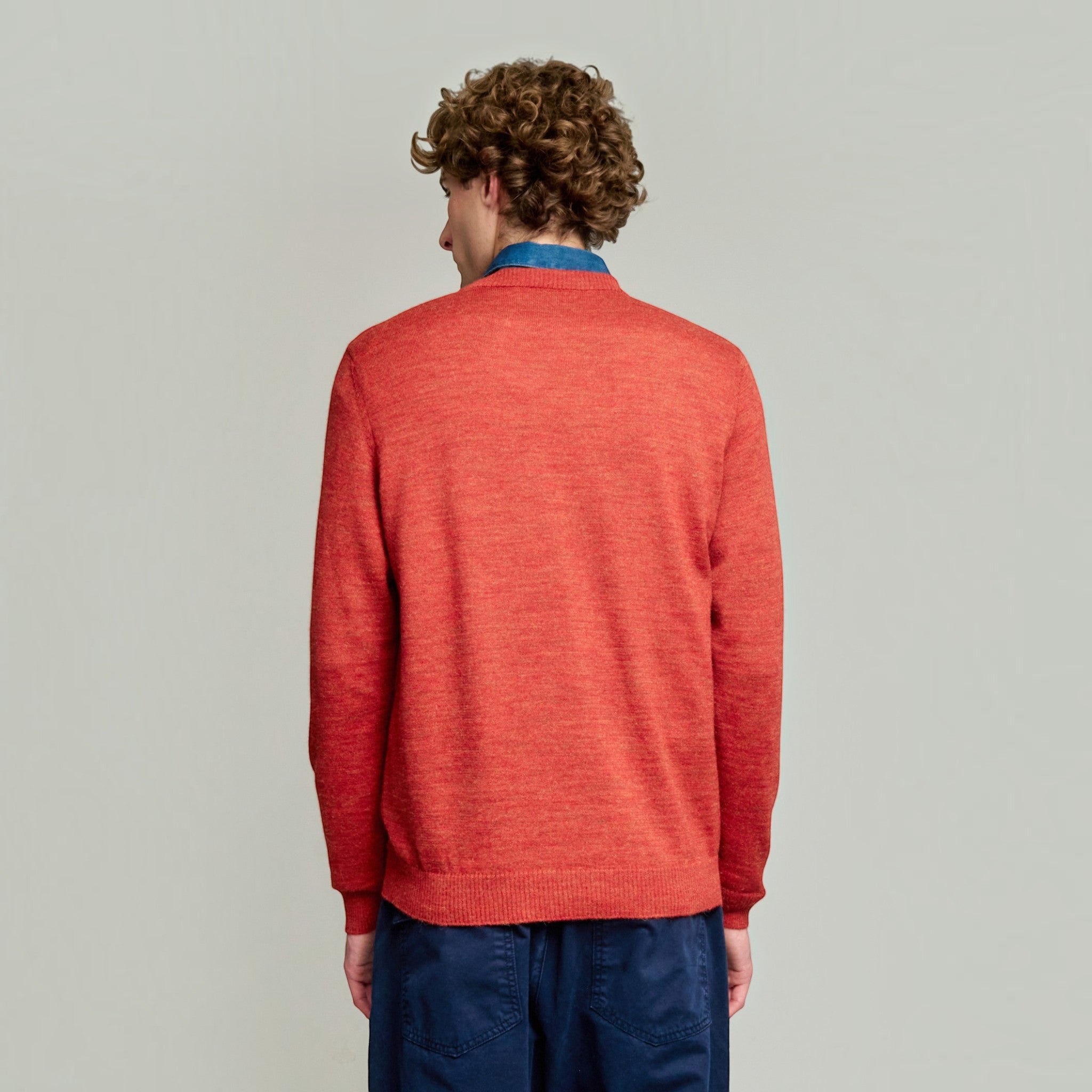 Model wearing a red 100% Baby Alpaca crew-neck sweater over a collared shirt