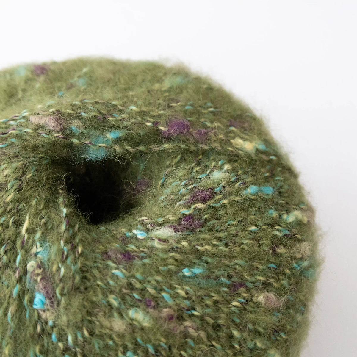 Close-up of Moss Green Indulge baby alpaca bouclé yarn showing its looped texture