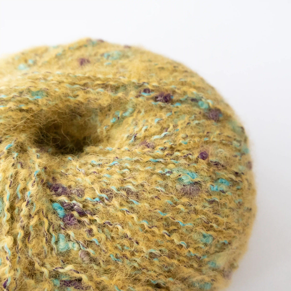 Close-up of Mustard Indulge baby alpaca bouclé yarn showing its looped texture