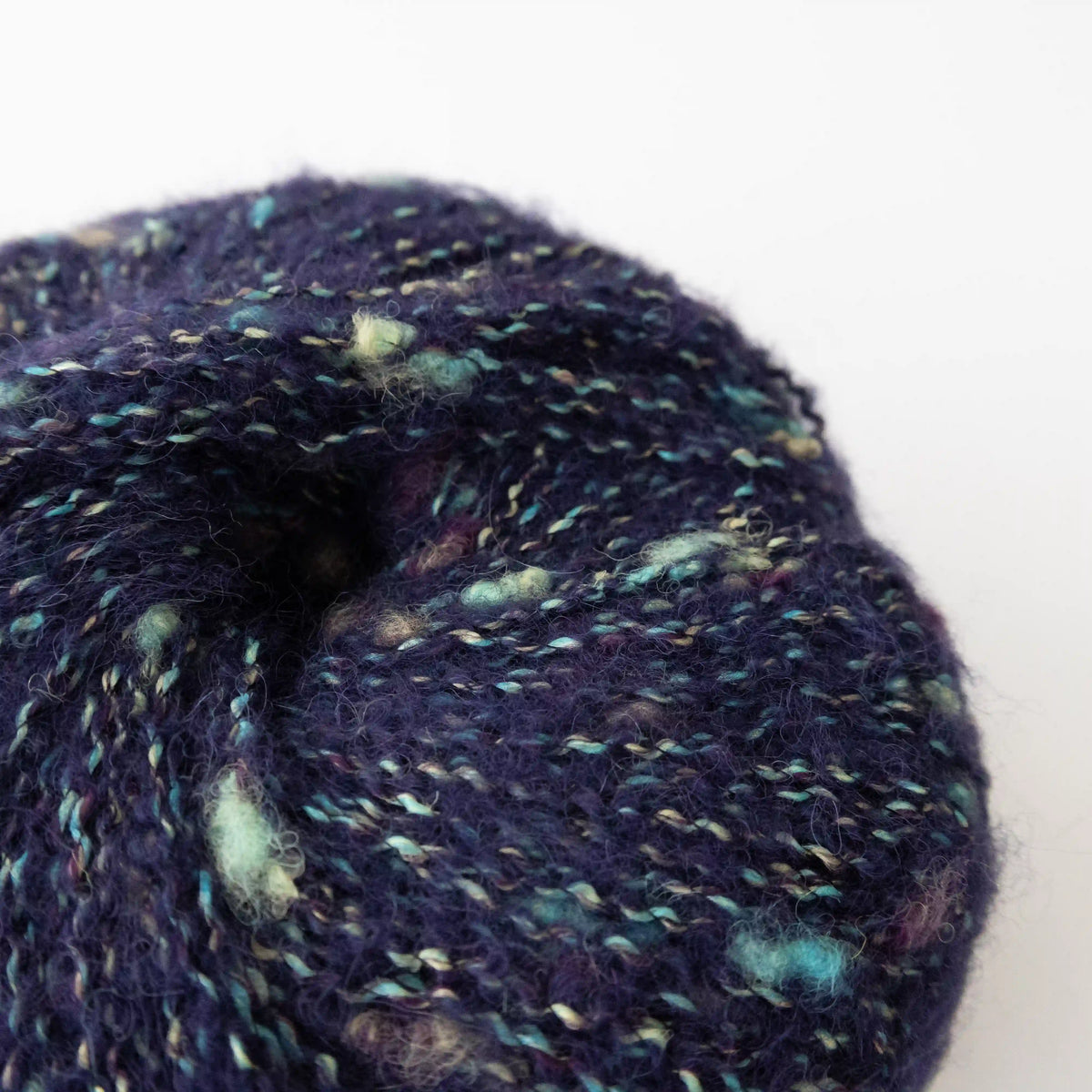 Close-up of Navy Indulge baby alpaca bouclé yarn showing its looped texture.