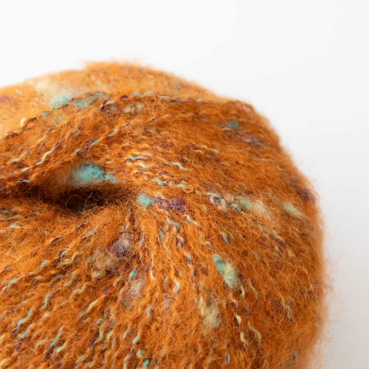 Close-up of Orange Indulge baby alpaca bouclé yarn showing its looped texture