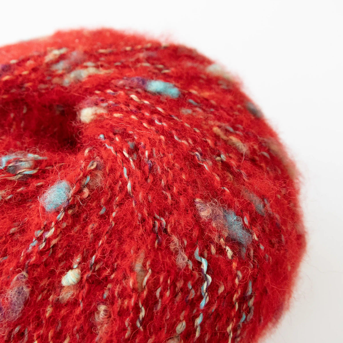 Close-up of Red Indulge baby alpaca bouclé yarn showing its looped texture.