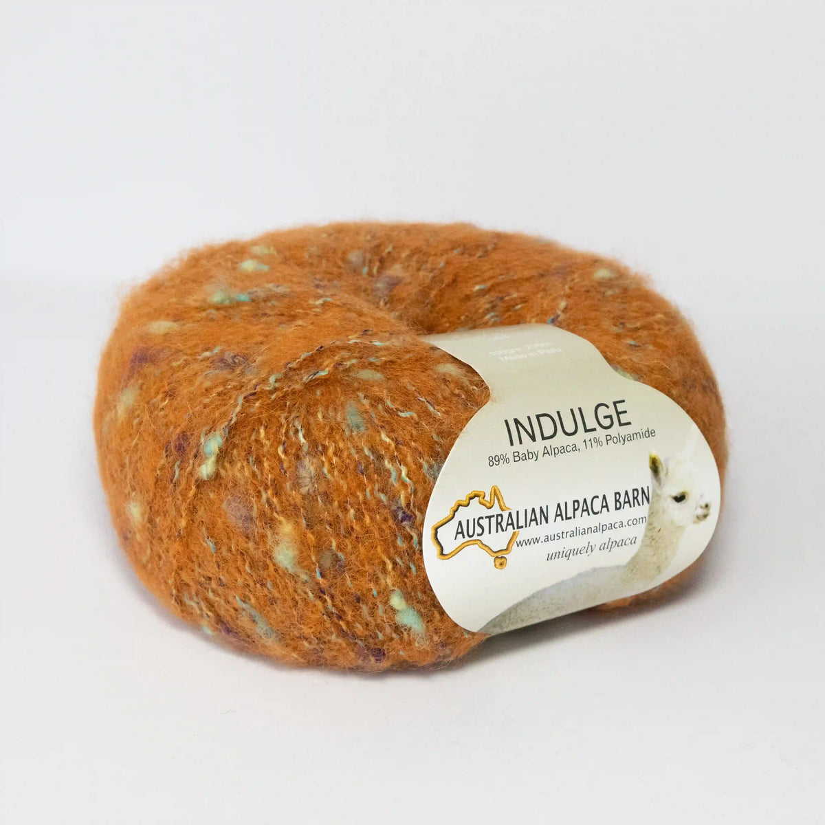 Orange Indulge baby alpaca bouclé yarn with its product label visible.